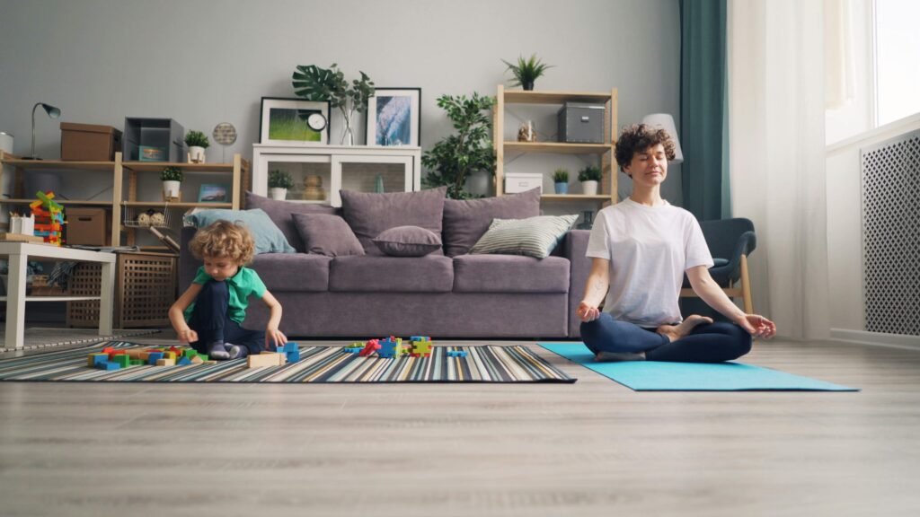A relaxed mother meditates while her son plays with building blocks in a cozy living room.