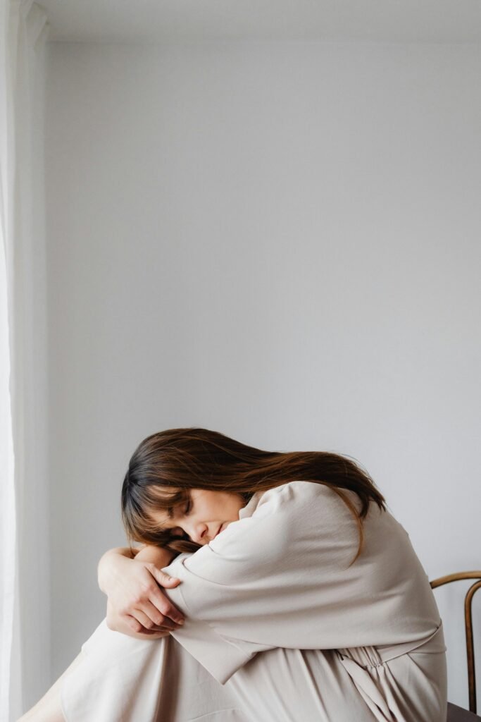 Woman in light dress resting peacefully indoors, embodying calmness.