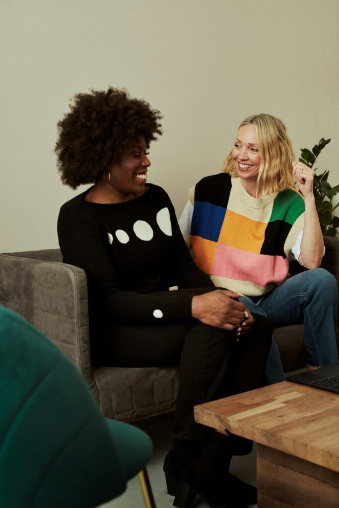 Two women enjoy a fun conversation on a sofa in a cozy living room setting.